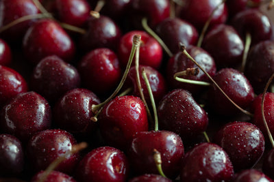 Fresh dark red cherries with stems, the fruit used in Jar Thuraya cherry jam