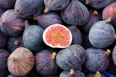 Fresh purple figs with one cut open to show the red interior